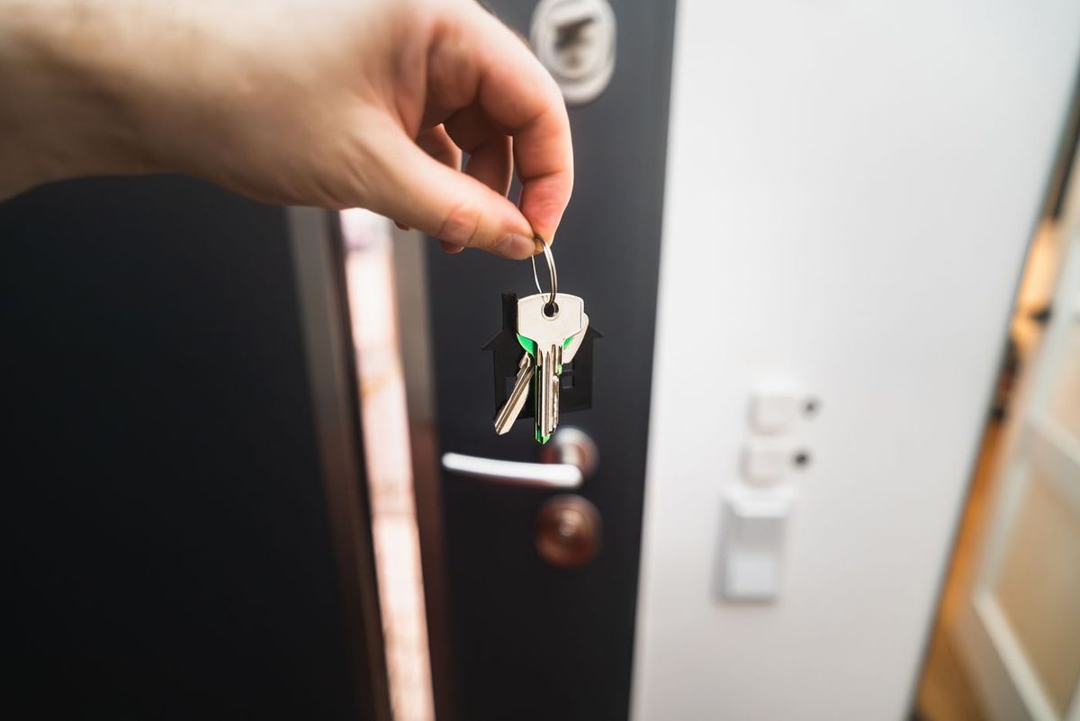 A hand turning a key in a front door lock
